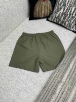 Pantaloncini casual verdi su divano con cuscini decorativi, stile rilassato e confortevole.