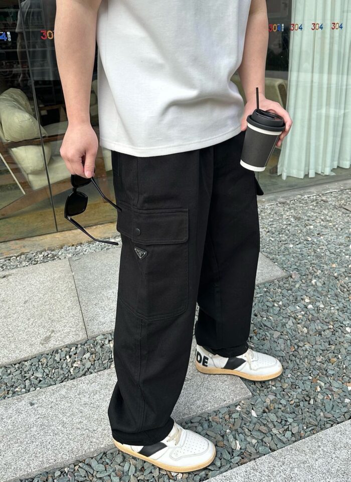 Persona stylish con t-shirt chiara, cargo neri, sneakers bianche, in città soleggiata.