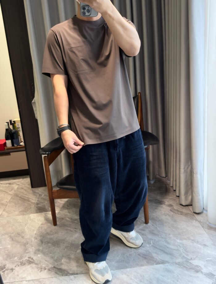 Persona in casual stile con t-shirt marrone, pantaloni larghi e sneakers in ambiente moderno.