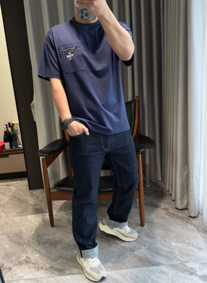 Abbigliamento casual con jeans scuri, t-shirt navy e sneakers bianche in ambiente moderno.