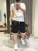 Look casual con T-shirt bianco, shorts neri con Cuffe e sneakers bianche.