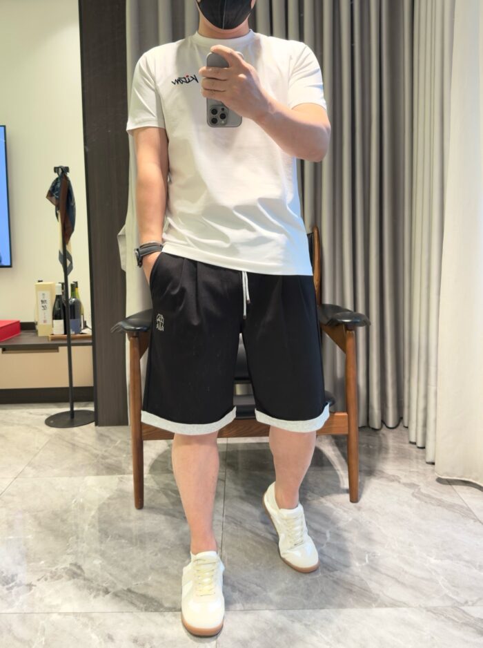 Look casual con T-shirt bianco, shorts neri con Cuffe e sneakers bianche.