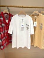 Abbigliamento casual: cardigan a quadri, T-shirt bianca e camicia beige su supporto in legno.