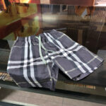Pantaloncini eleganti in tartan grigio con coulisse verde acqua, perfetti per lestate casual.