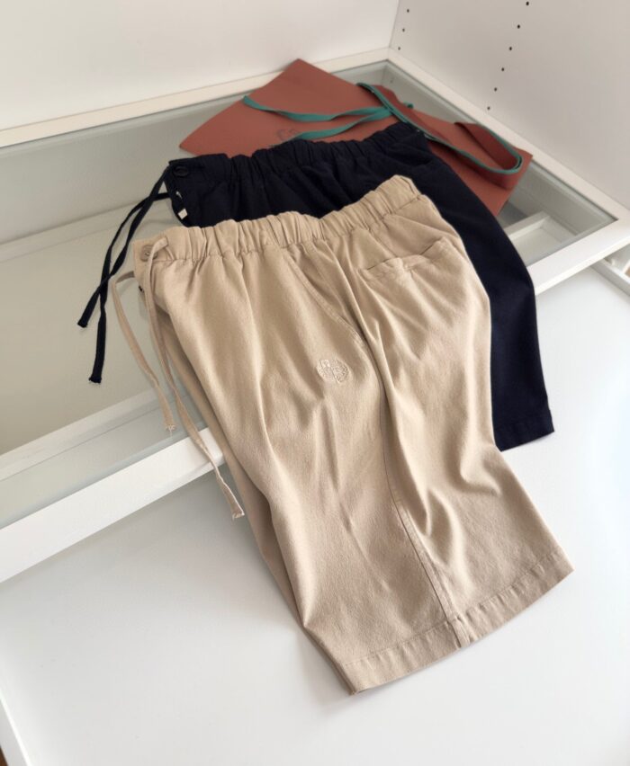 Pantaloncini casual beige e neri con accessorio estivo, look fresco e versatile per lestate.