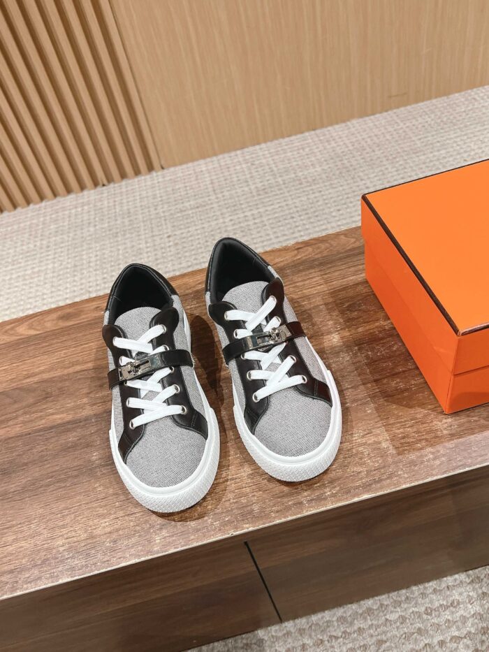 Sneakers eleganti grigio e nero con scatola arancione su superficie in legno.