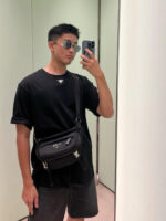 Young man taking a trendy selfie with sunglasses and backpack in stylish minimalistic setting.