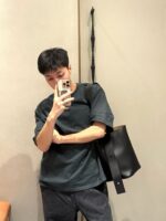 Ragazzo con T-shirt verde, borsa nera, selfie in stile casual e moderno.