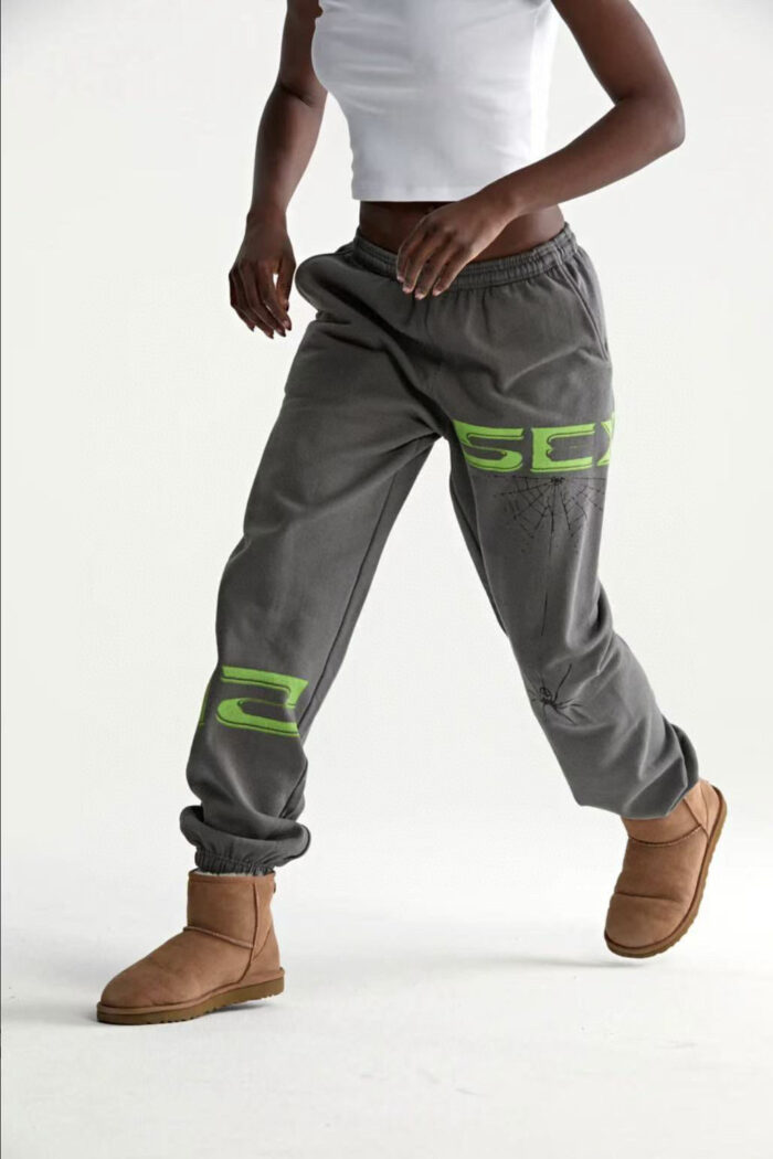 Modella in movimento con joggers grigi, maglietta bianca e stivali castani casual.