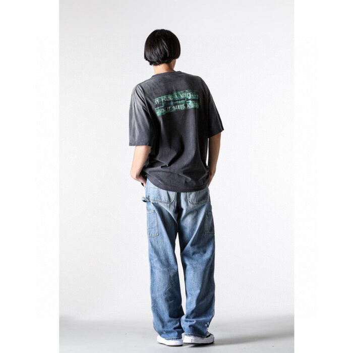 Ragazzo in casual streetwear con jeans oversize e sneakers bianche, vista da dietro.