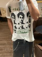 Selfie casual con T-shirt grafica, mascherina azzurra e stile rilassato in ambiente moderno.