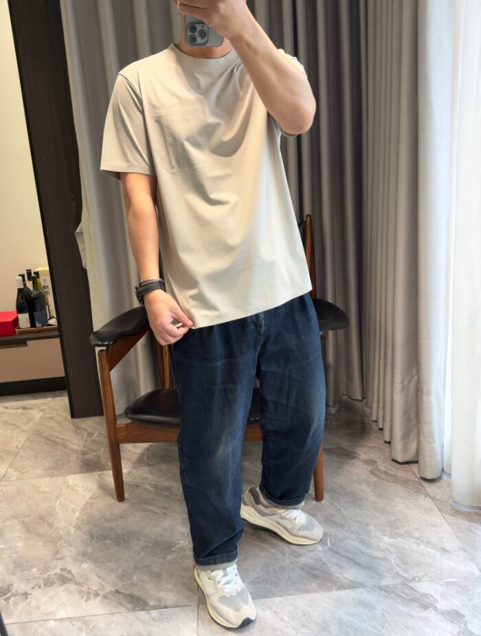 Giovane uomo casual con t-shirt beige e sneakers bianche in ambiente moderno e luminoso.