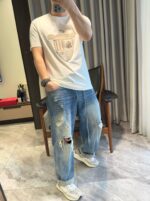 Selfie casual con jeans distressed, t-shirt semplice e sneakers moderne in ambiente elegante.