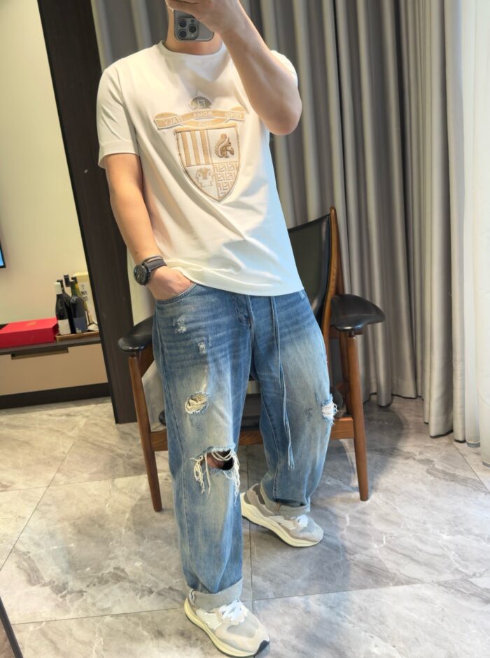 Selfie casual con jeans distressed, t-shirt semplice e sneakers moderne in ambiente elegante.