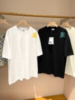 Magliette streetwear bianca e nera con grafiche colorate su supporto in legno, stile minimalista.
