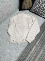 Camicia leggera a righe su divano accogliente con cuscini e stile casual elegante.