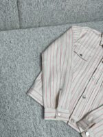 Camicia a righe casual con bottoni, su sfondo grigio elegante, stile estivo e rilassato.