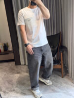 Selfie in stile casual con maglietta bianca, pantaloni grigi e sneakers comodi.