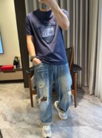Selfie in stile casual con jeans strappati e t-shirt navy in soggiorno moderno.