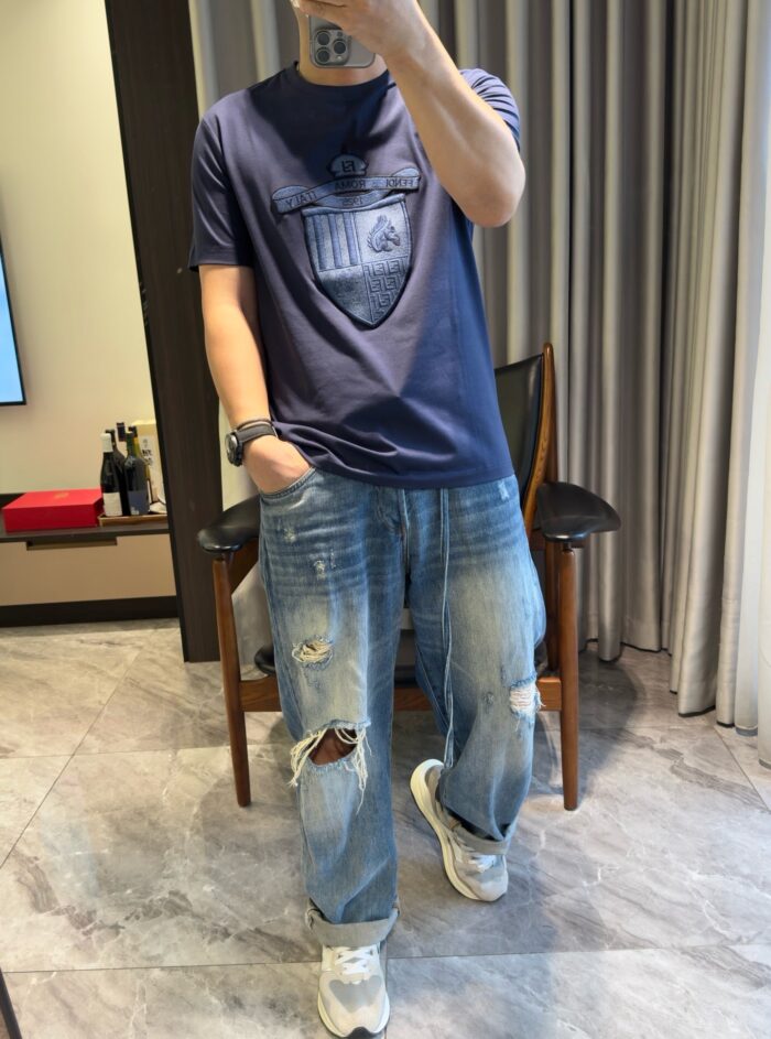 Selfie in stile casual con jeans strappati e t-shirt navy in soggiorno moderno.