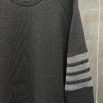 Maglione raglan nero con tre strisce grigie, stile sportivo e design casual elegante.