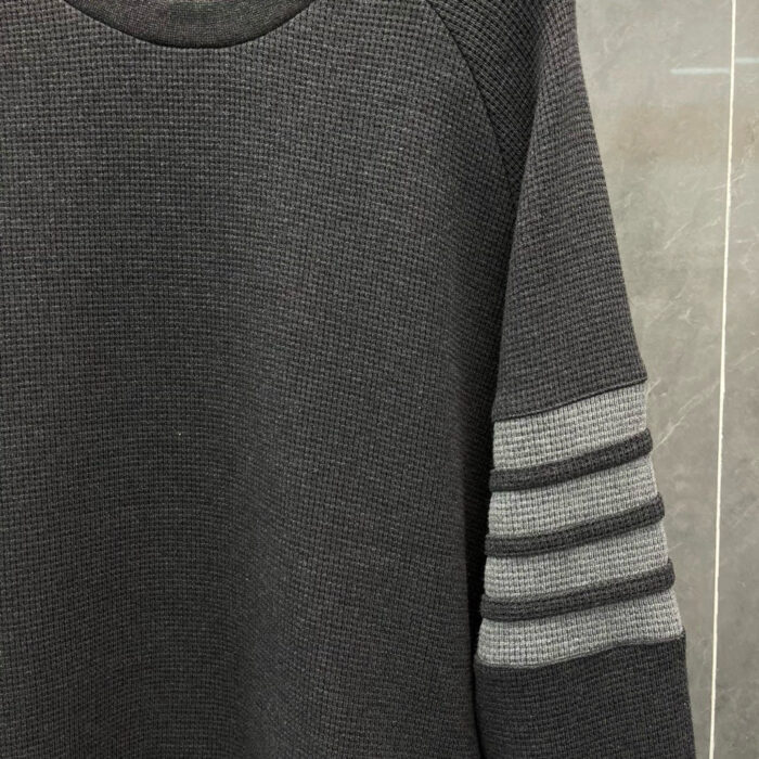Maglione raglan nero con tre strisce grigie, stile sportivo e design casual elegante.