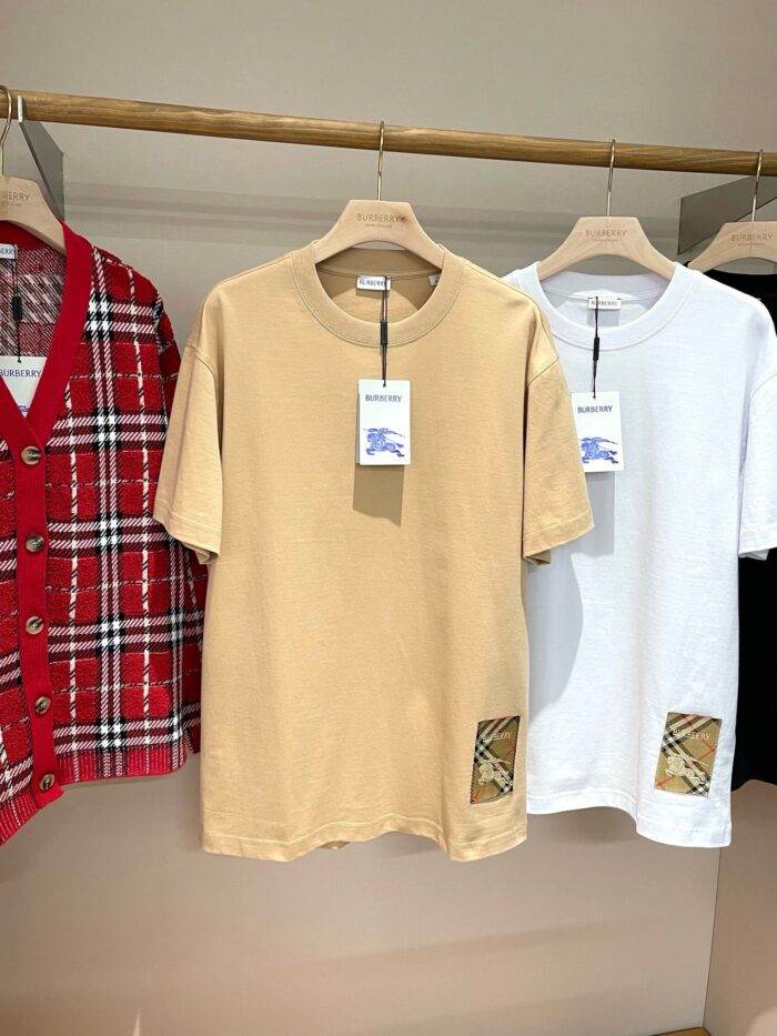 Vetrina con magliette casual beige e bianca, cardigan rosso a quadri e dettagli di moda