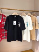 Esposizione di magliette casual con ricami e camicia a quadri in boutique moderna.