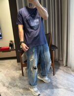 Persona che scatta selfie in stile casual urbano, jeans distressed e sneakers leggeri.
