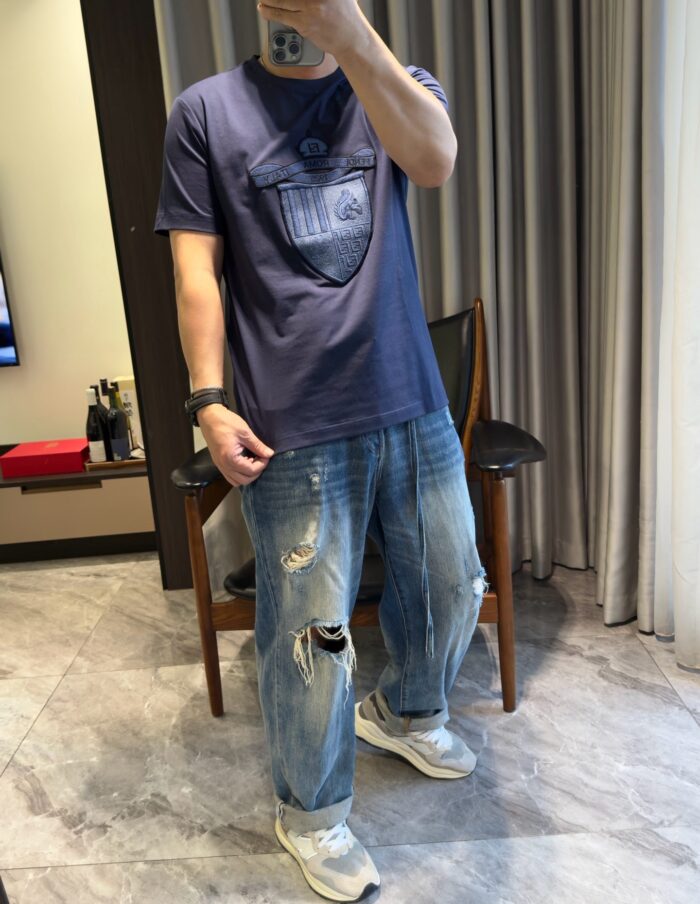 Persona che scatta selfie in stile casual urbano, jeans distressed e sneakers leggeri.