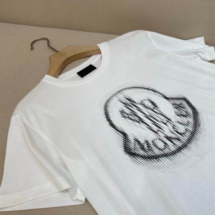 T-shirt bianca con grafica MOC e logo centrale, stile casual e moderno.