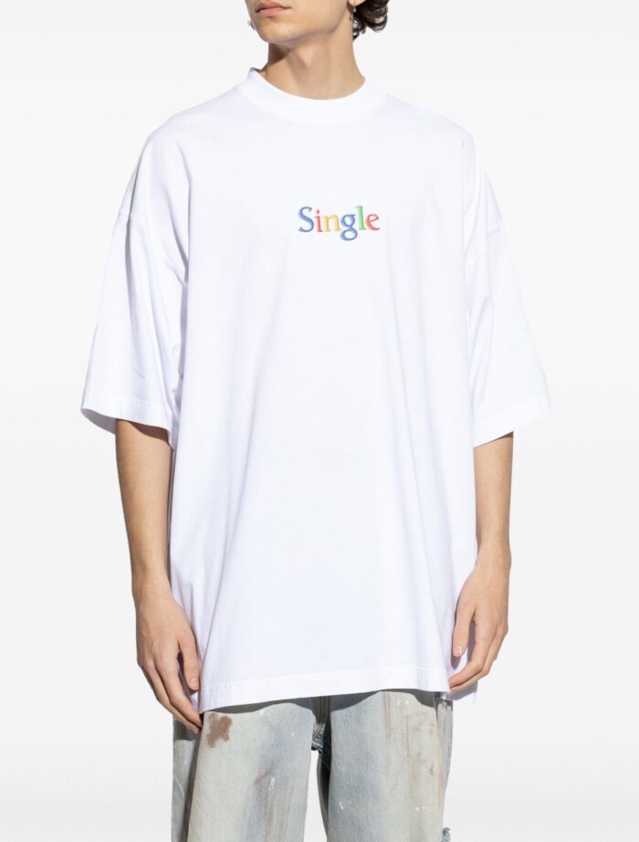 T-shirt oversized bianco con grafica colorata Single e jeans denim sdruciti, stile streetwear casual.