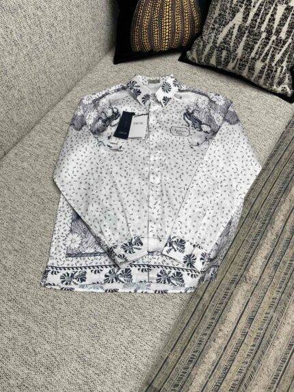 Camicia bianca elegante con motivi floreali su divano decorato, stile casual e raffinato.