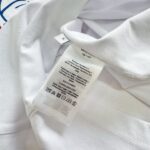 Camicia bianca casual con etichetta di cura e dettagli di branding sul colletto.