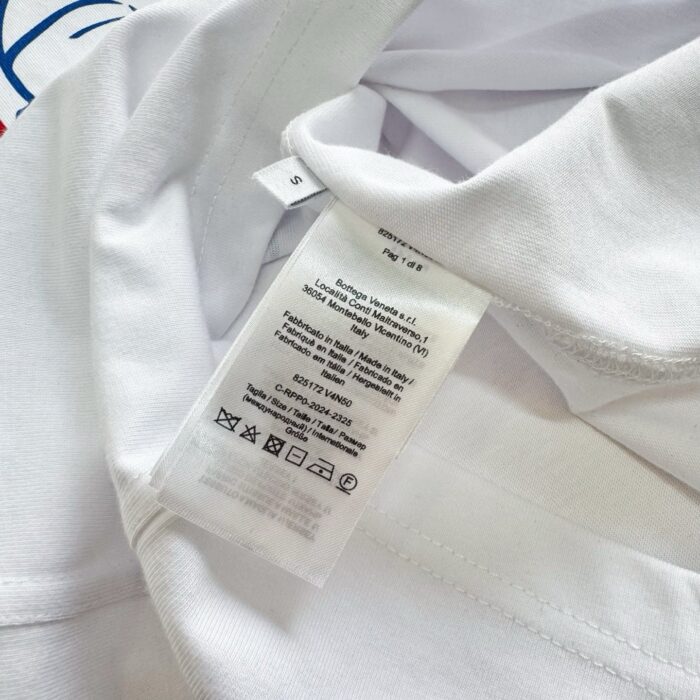 Camicia bianca casual con etichetta di cura e dettagli di branding sul colletto.