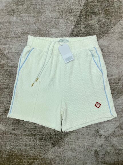 Pantaloncini bianchi casual con coulisse, tasche e dettagli blu, logo rosso sul lato.