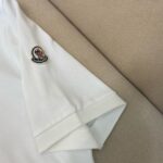 T-shirt bianca casual con ricamo, maniche arrotolate su sfondo beige, stile semplice e di qualità.