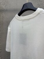 Maglietta bianca casuale su appendino nero, stile minimalista e comfort moderno.