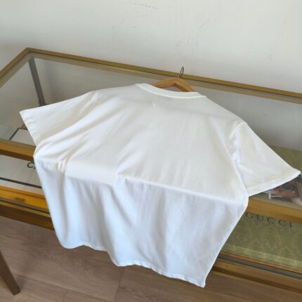 Maglietta bianca semplice su tavolo di vetro, ideale per look minimalisti e casual.