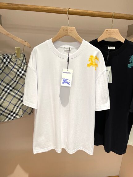 T-shirt bianco con graphic giallo, nero minimalista vs shorts scozzese, look estivo casual.