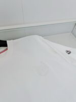 Maglietta bianca minimalista con logo embossato, dettaglio rosso e tessuto morbido.
