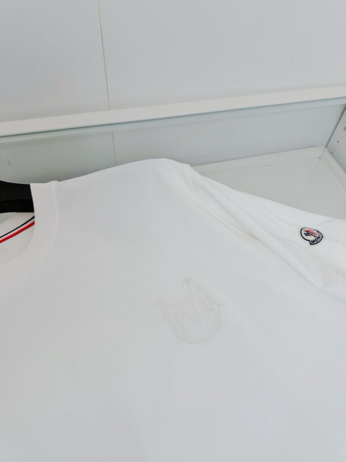 Maglietta bianca minimalista con logo embossato, dettaglio rosso e tessuto morbido.