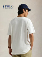 Uomo casual con polo Ralph Lauren, t-shirt bianco, pantaloncini khaki e cappello navy.