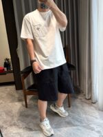 Giovane in abbigliamento casual con shorts e sneakers in ambiente moderno e luminoso.