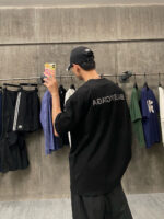 Giovane con cappello scatta selfie in negozio di abbigliamento casual industriale.