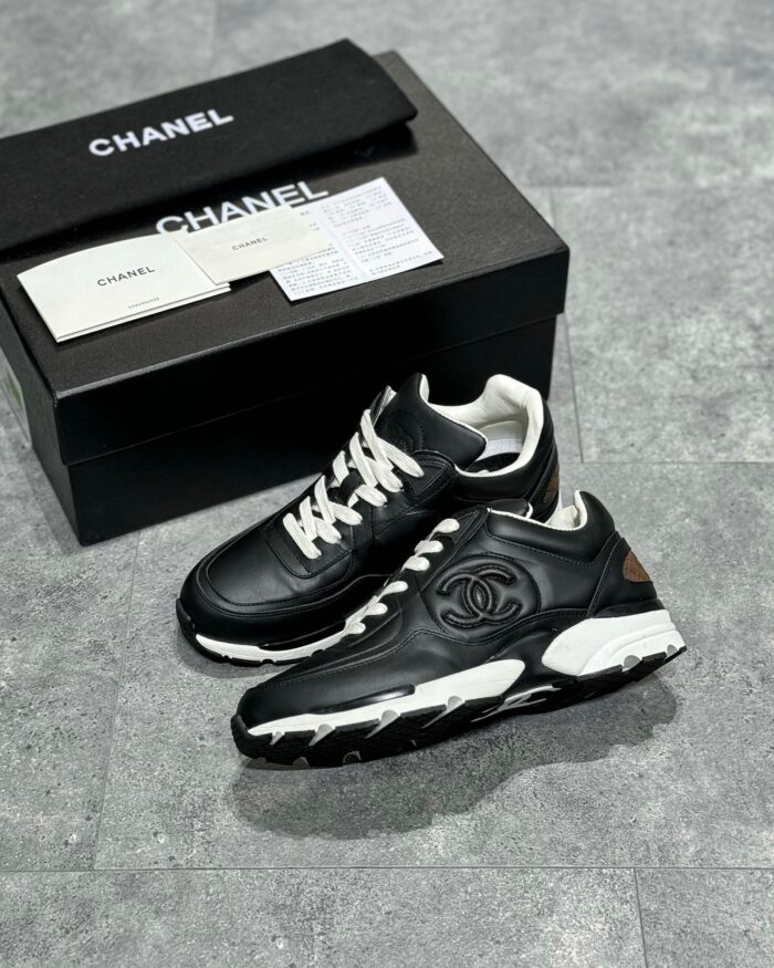Sneakers Chanel in pelle nera e bianca, stile elegante e packaging luxury.