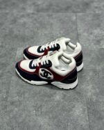 Sneakers Chanel bianche con dettagli navy e rosso, stile sportivo e di lusso.