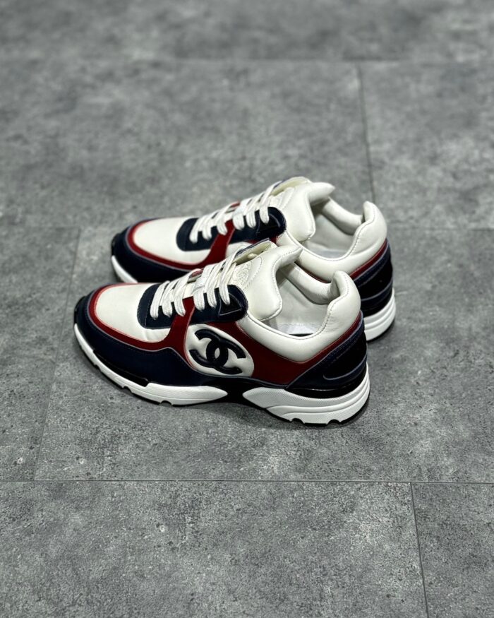 Sneakers Chanel bianche con dettagli navy e rosso, stile sportivo e di lusso.