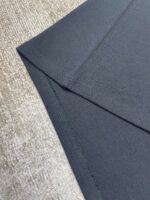 Tessuto grigio elegante con piega raffinata e sfondo contrastante, perfetto per abbigliamento e interior design.