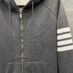 Felpa grigia con zip, cappuccio, strisce bianche e stile sporty casual.